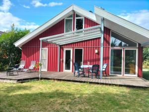 a red house with a table and chairs on a deck at Ferienhaus Büffel mit Sauna in Twist in Twist