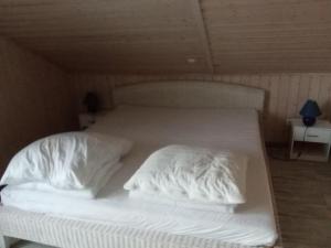 a bed with white sheets and pillows on it at Ferienhaus Büffel mit Sauna in Twist in Twist