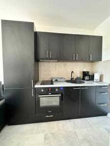 - une cuisine avec des armoires noires et une cuisinière dans l'établissement Apartman Joka, à Veliko Gradište