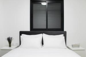 a bedroom with a bed with white pillows and a window at Penthouse #47 By Hashdera Eilat in Eilat