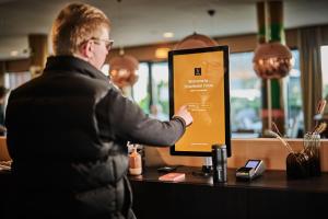 Een man aan een balie die een bord omhoog houdt. bij Smarthotel Forus in Stavanger