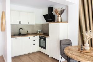 a kitchen with white cabinets and a wooden table at Ferienanlage Villa Maare in Gillenfeld