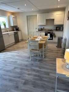 a kitchen with white cabinets and a table and chairs at The Jockey's Lodge @ Danebury in Stockbridge