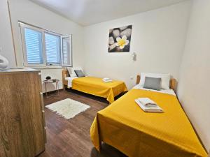 duas camas num quarto com lençóis amarelos em Apartments Vuckovic em Razanj