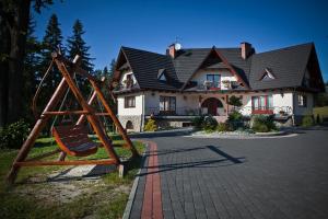 a large house with a playground in front of it at Sykowny Dworek Apartamenty in Kościelisko