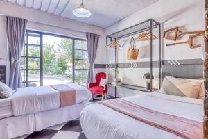 um quarto de hotel com duas camas e uma cadeira vermelha em The Bedford Manor em Centurion