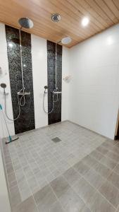 a bathroom with two showers and a tiled floor at JM Rally Parc Ferme Rallimuseo in Tuuri