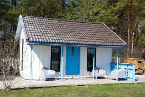 a small white shed with chairs and a blue door at Lõunaranna Harbour Accommodation in Simisti