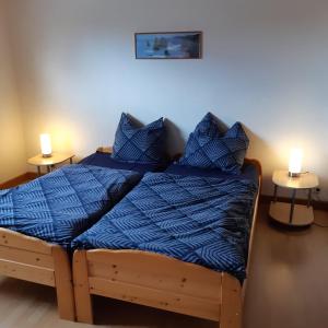 a bedroom with a bed with blue sheets and two lamps at Nordseeferienhaus-Alma in Niebüll