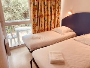 een hotelkamer met 2 bedden en een raam bij Arc en Ciel Oléron in Saint-Trojan-les-Bains