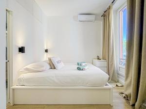 ein weißes Bett in einem Zimmer mit Fenster in der Unterkunft Chic scandinavian style - Wifi, AC, 2pers in Nizza