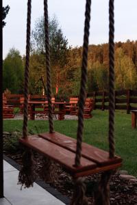 a wooden swing in a park with benches in the background at Domek w sercu Kaszub in Dziemiany