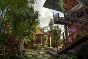 un patio de una casa con una escalera y palmeras en d'kamala, en Ubud