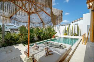 a bed and an umbrella on a balcony with a swimming pool at Villa Rosado Canggu in Tumbak Bayuh