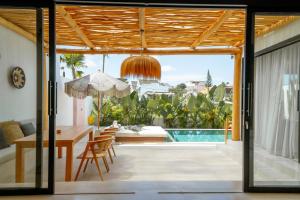 a dining room with a table and a view of a pool at Villa Rosado Canggu in Tumbak Bayuh