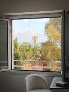 a window with a view of a palm tree at Plage à 200 mètres. Vue mer et Esterel ! Rénové in Saint-Raphaël