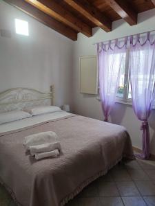 ein Schlafzimmer mit einem Bett mit lila Vorhängen und einem Fenster in der Unterkunft A casa di Mimma in Palazzo Adriano