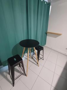 einen Tisch und zwei Hocker in einem Zimmer mit einem grünen Vorhang in der Unterkunft Room B777 AF in Papeete