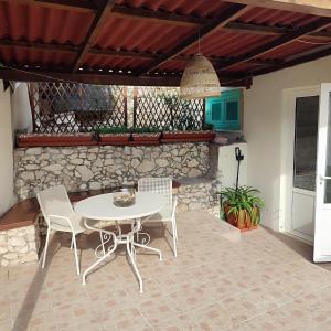 a patio with a table and chairs and a stone wall at Guest House Vuljan in Hvar