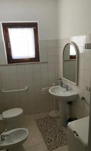 y baño con 2 aseos, lavamanos y espejo. en B&B Villa Rosina, en Satriano di Lucania
