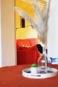 a table with a red couch and a bottle of wine at Quick Home - Magnolia in Viverone +7 photos