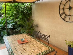 een tafel en stoelen op een patio met een klok bij Les Lauriers Duplex centre ville avec jardin in Nyons
