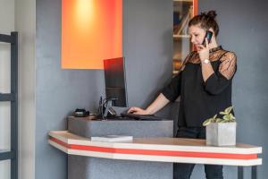 Eine Frau, die auf einem Handy an einem Schreibtisch redet. in der Unterkunft Zenitude Hôtel-Résidences Nantes Métropole in Nantes