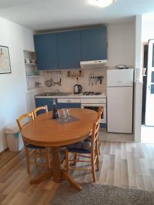 a kitchen with a wooden table and a kitchen with a refrigerator at Apartman Miro in Cavtat