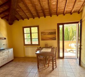 a kitchen with a wooden table and a dining room at Relais Poggio Del Melograno in Montecatini Val di Cecina