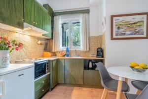 a kitchen with green cabinets and a table with chairs at Monte Verde Apartment 102 in Dhematorá