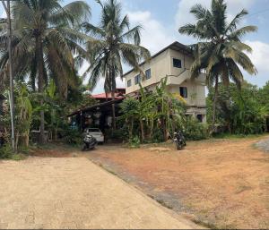 ein Haus mit Palmen und einem Motorrad, das davor geparkt ist in der Unterkunft KENSONS BUDGETSTAY NON AC FREE WIFI and PARKING in Mangaluru