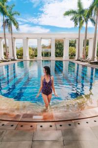a woman standing in the water in a swimming pool at Indochine Palace in Hue