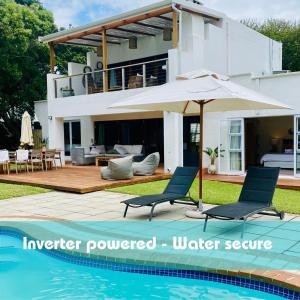 a villa with a swimming pool and an umbrella at Woodlands Beach Villa in Southbroom