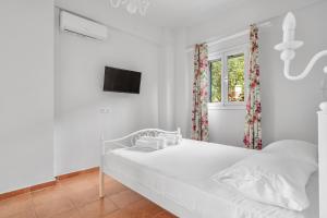 a white bedroom with a bed and a window at Monte Verde Apartment 102 in Dhematorá