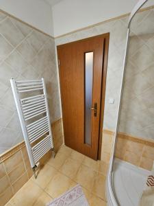 uma casa de banho com um chuveiro e uma porta de madeira em St. Florian Restaurant & Pension em Vrakúň