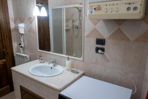 uma casa de banho com um lavatório e um chuveiro com um espelho. em Appartamento Talia em Bevagna