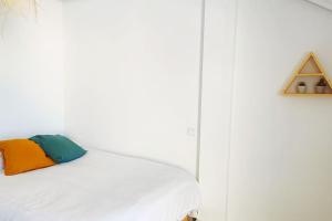 Una cama blanca con una almohada colorida. en Casa Maui: Apartamento para 6 con piscina, en San Mamés de Meruelo