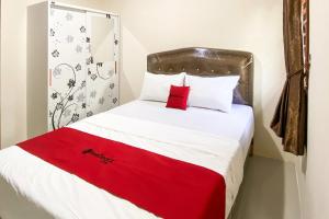 a bedroom with a bed with a red blanket on it at RedDoorz Near Batu Ampar Harbour in Jodoh