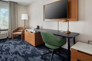 um quarto de hotel com uma secretária, uma televisão e uma cadeira em Fairfield by Marriott Rochester Henrietta/University Area em Henrietta