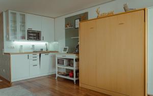une cuisine avec des placards blancs et une grande porte en bois dans l'établissement Appartement Honey, à Sankt Englmar
