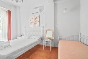 a white bedroom with two beds and a mirror at Monte Verde Apartment 101 in Dhematorá