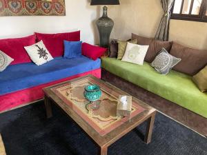ein Wohnzimmer mit farbenfrohen Sofas und einem Couchtisch in der Unterkunft VILLA ALWAN BARAKA - Sans vis à vis, Piscine chauffée, Hammam, Personnel in Essaouira