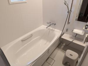 uma banheira branca na casa de banho com um chuveiro em ECHO em Yonezawa