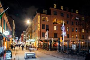 a city street at night with people walking down the street at Queen's Hotel by First Hotels in Stockholm