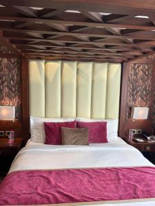 a bedroom with a large bed with red pillows at Saura Hotel, Agra in Agra
