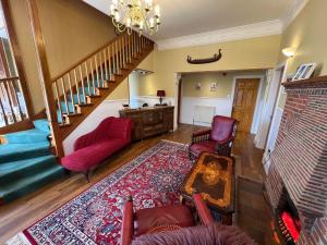 a living room with red chairs and a staircase at Herrislea House Hotel in Tingwall