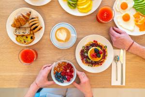 zwei Personen sitzen an einem Tisch mit Frühstückslebensmitteln in der Unterkunft Hotel Estense in Gatteo a Mare