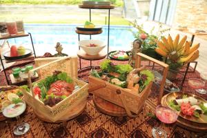 ein Tisch mit mehreren Körben Essen drauf in der Unterkunft Facade Hotel by Azana in Tawangmangu