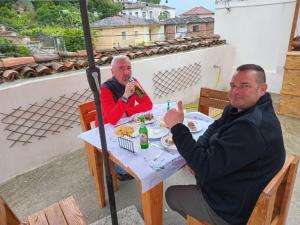 two men sitting at a table eating food at Te MuzzeU Hostel in Berat