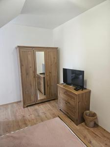 uma sala de estar com uma televisão e uma cómoda com um espelho em St. Florian Restaurant & Pension em Vrakúň